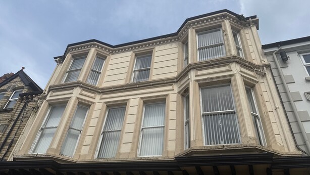 Un immeuble d’angle doté de grandes baies vitrées et d’un style architectural classique.