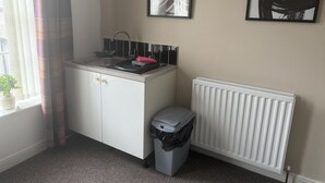 Une petite cuisine équipée d’un évier, d’un radiateur et d’une poubelle.