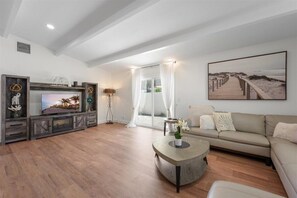 Ein Wohnzimmer mit Fernseher, Sofa, Couchtisch und Kunstwerken.