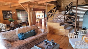 A wooden interior with a sofa, ottoman, and a staircase. - Panoramic Mountain Views - Luxury Hilltop Retreat in Jardín de Dota (San José)