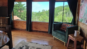 A wooden cabin interior with a sofa, a small table, a TV, and a painting on the wall. - Panoramic Mountain Views - Luxury Hilltop Retreat in Jardín de Dota (San José)