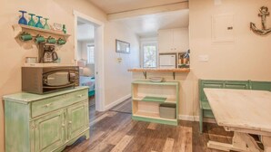 A kitchen with a microwave, coffee maker, and green cabinets.