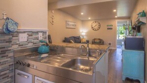 A kitchen with a stainless steel stove, double sink, and a blue kettle.