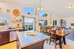 A spacious kitchen with a large island, a dining area with wooden chairs, and a view of the outdoors.