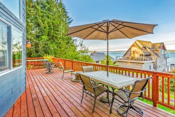 A wooden deck with outdoor furniture, a table, and an umbrella.