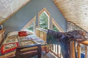 A bedroom with a large bed, a wooden headboard, and a view of the outdoors through a window.