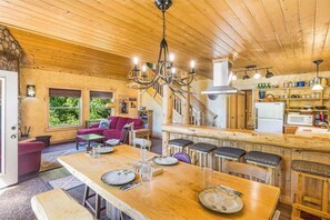 A wooden interior with a dining area, kitchen, and a staircase.