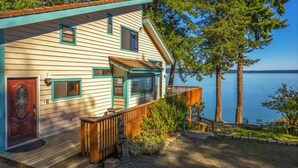 Une maison avec une terrasse, une porte rouge et une vue sur un lac.