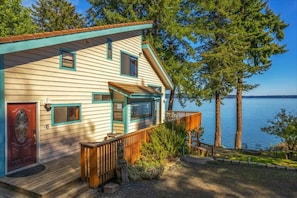 A house with a deck, a red door, and a view of a lake. - 4BR Waterfront Home | Sauna | Dock | Firepit (Brinnon)