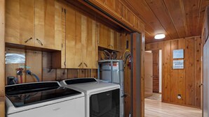 A compact kitchen with wooden cabinets, a washing machine, and a dryer. - Waterfront Haven: Beach Access, Hot Tub, Fire Pit (Shelton)