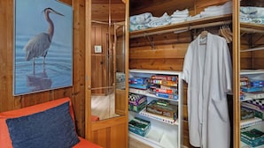 A wooden interior with a framed picture of a bird, a glass door leading to a storage area, and a rack with folded towels. - Waterfront Haven: Beach Access, Hot Tub, Fire Pit (Shelton)