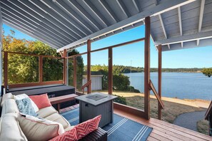 Un espace extérieur aménagé, abrité et doté de sièges, offrant une vue sur un lac.