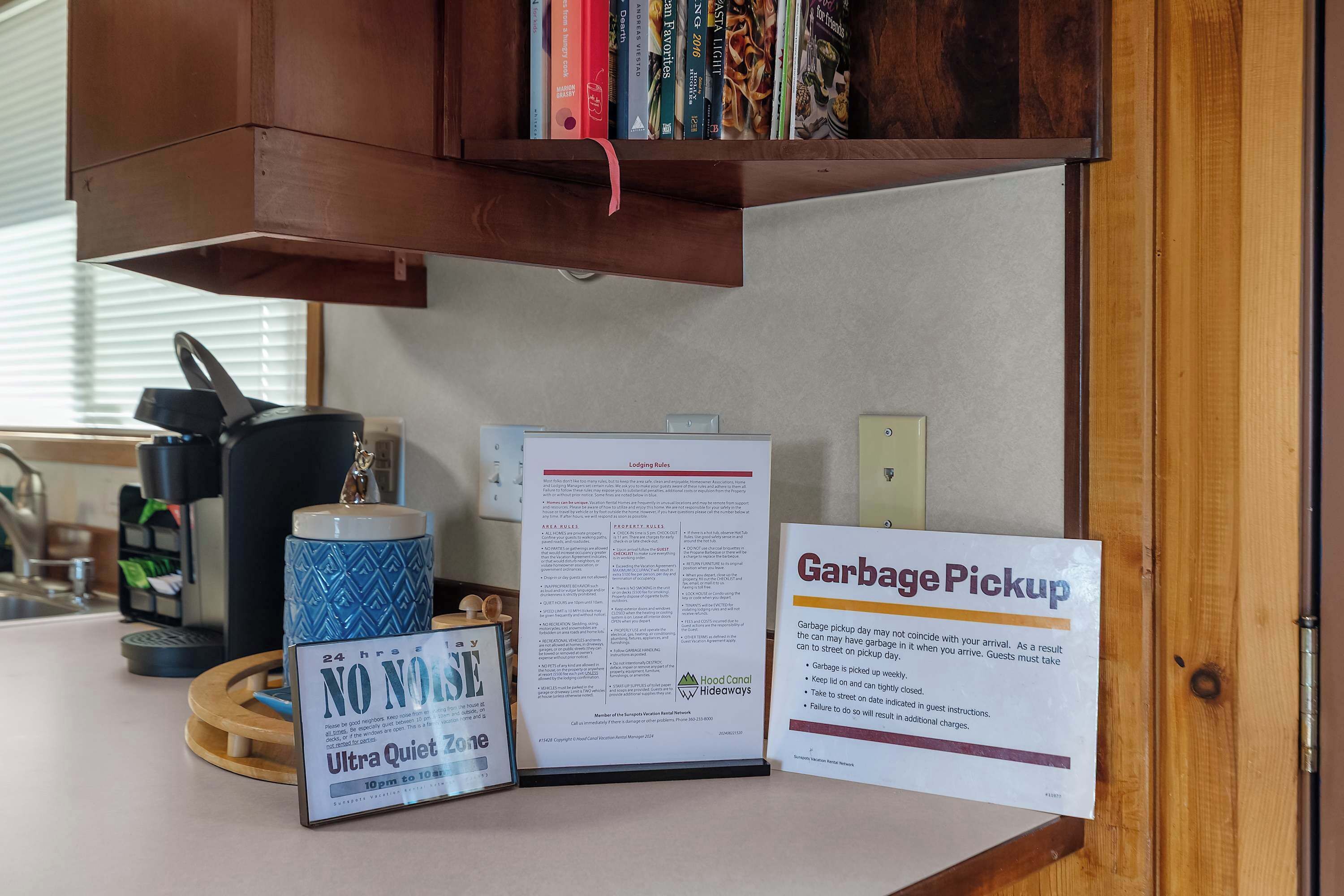 A kitchen area with a coffee machine, a mug, a sign for 'Ultra Quiet Zone', and a 'Garbage Pickup' notice.
