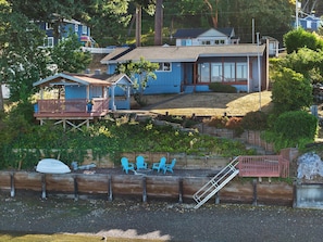 A residential property with a dock, a covered deck, and a house with a large window.