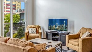 A modern living room with a large window, a flat-screen TV, and two sofas.