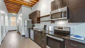 A modern kitchen with stainless steel appliances, wooden ceiling beams, and a view to the left.