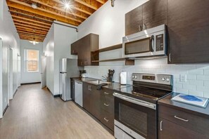Una cocina moderna con electrodomésticos de acero inoxidable, vigas de techo de madera y vistas al izquierda.