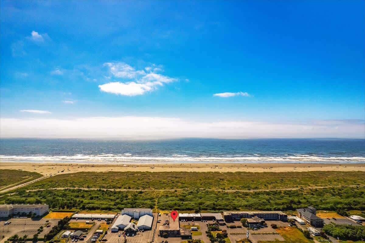An aerial view of a coastal area with a beach, buildings, and a clear sky.