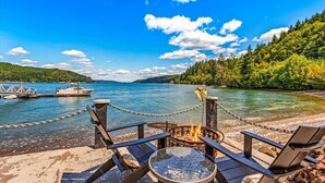 Ein Deck am See mit Stühlen, einer Feuerstelle und einer Kettenbarriere.