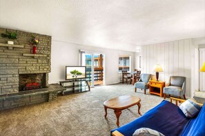 Ein Wohnzimmer mit Kamin aus Stein, einer Couch, einem Couchtisch und einem Bücherregal.