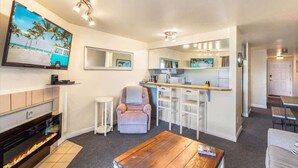 A modern living room with a fireplace, a TV, a bar area, and a seating area. - 1BR Condo | Dogs OK | Close to Ocean & Town (Ocean Shores)