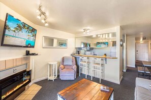 A modern living room with a fireplace, a TV, a bar area, and a seating area. - 1BR Condo | Dogs OK | Close to Ocean & Town (Ocean Shores)