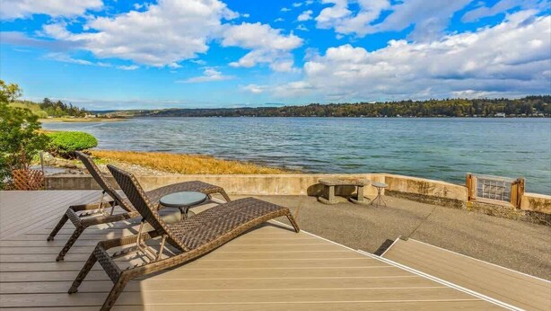A deck with lounge chairs and a table overlooking a body of water.