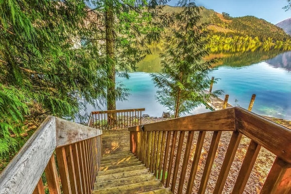 A wooden staircase leading to a lake with surrounding trees.