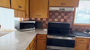 A kitchen with wooden cabinets, a microwave, a stove, and a Whirlpool range hood.