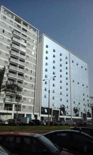 A multi-story building with balconies, a reflective glass facade, and a parking lot with cars. - Wonderful 4-bedroom apartment in San Miguel perfect for your stay (San Miguel)