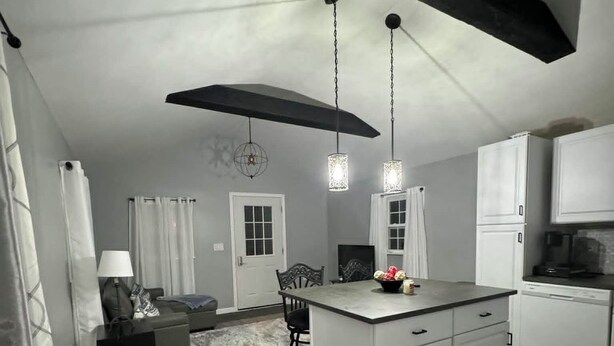 Een moderne keuken met een centraal eiland, hanglampen en een zithoek met een bank en tafel.