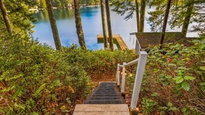 A wooden staircase leading to a dock over a lake, surrounded by trees and foliage. - Lakefront House: Private Dock, Forest Views, (Shelton)