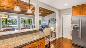 A kitchen with a granite countertop, wooden cabinets, and a stainless steel refrigerator. - Lakefront House: Private Dock, Forest Views, (Shelton)