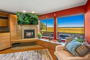 A living room with a fireplace, large windows, and a view of a field.