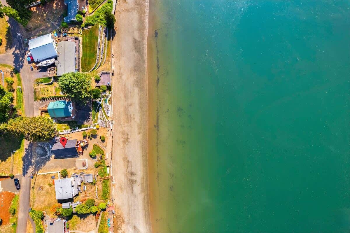 Ett flygbildsbild av ett kustnära område med byggnader, en strand och en väg.