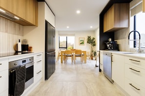 Eine moderne Küche mit Essbereich, Holzschränken, einem Kühlschrank und einer Kaffeemaschine.