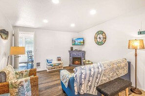 Una sala de estar con chimenea, televisor y sofá.