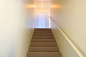 A carpeted staircase leading to a white door with a light fixture above. - Maris Stella Condo | Queen Beds | Unit C (Ocean Shores)