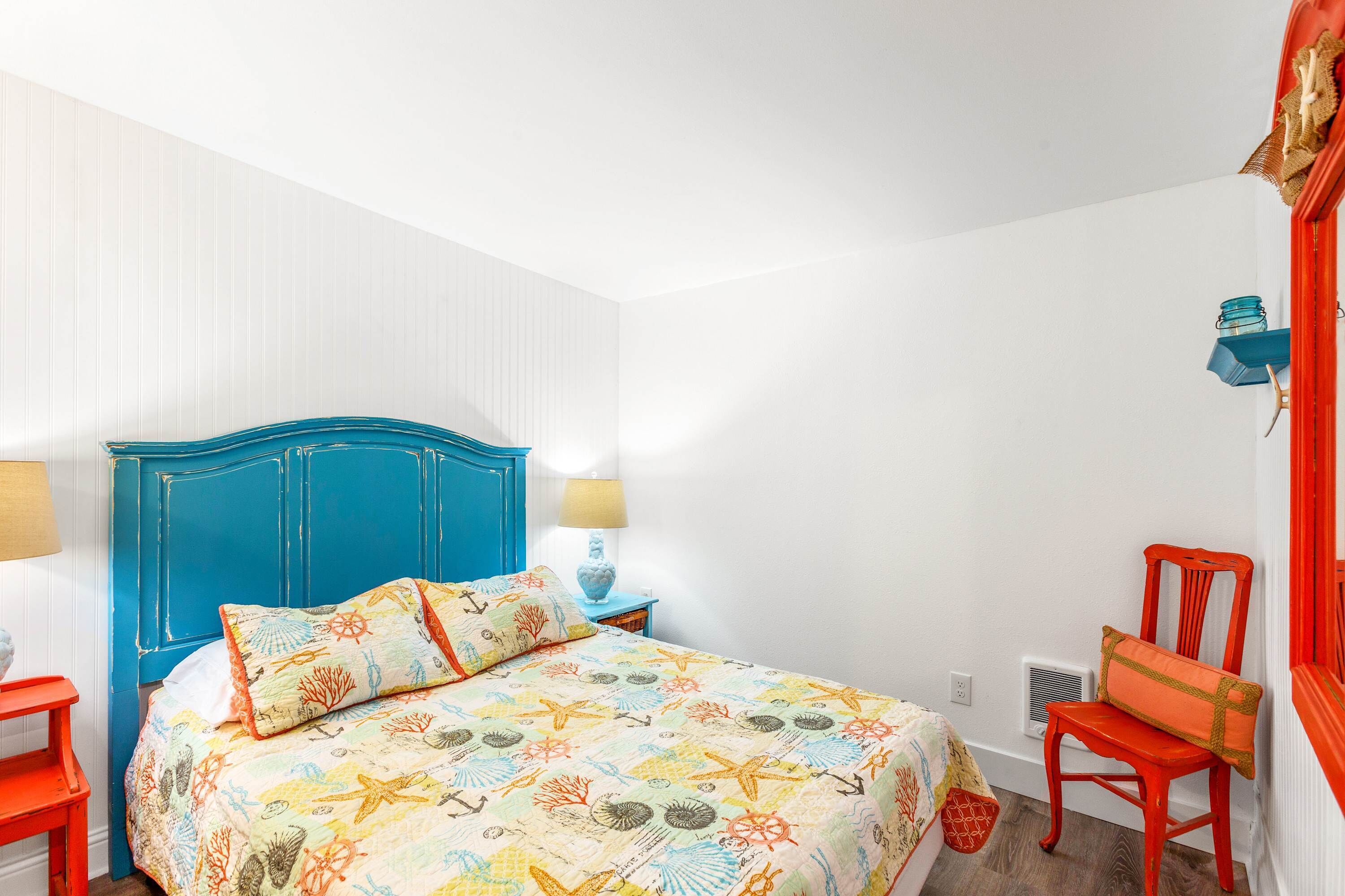 Um quarto com uma cama, uma cadeira, uma mesinha de cabeceira e um abajur.