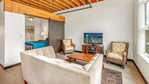 A living room with a sofa, two armchairs, a coffee table, a television, and a cityscape view. - Bremerton Bay Condo | Walk to Ferry | Unit 202 (Bremerton)