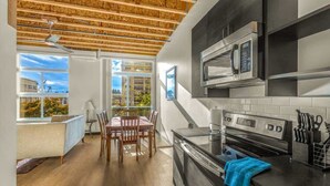 A modern kitchen with a wooden ceiling, built-in appliances, and a dining area with a view. - Bremerton Bay Condo | Walk to Ferry | Unit 202 (Bremerton)