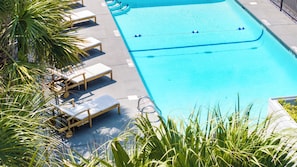 A swimming pool with lounge chairs and palm trees. - The Sandstone - 4BR Oceanfront Unit w/ Pool (Sleeps 10) (North Myrtle Beach)
