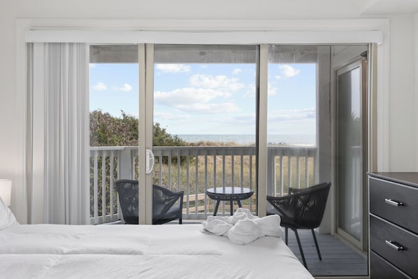 A bedroom with a bed, a small table, two chairs, and a dresser. - The Sandstone - 4BR Oceanfront Unit w/ Pool (Sleeps 10) (North Myrtle Beach)