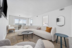 Ein modernes Wohnzimmer mit einer Eckcouch, einem runden Couchtisch und einem kleinen Beistelltisch.