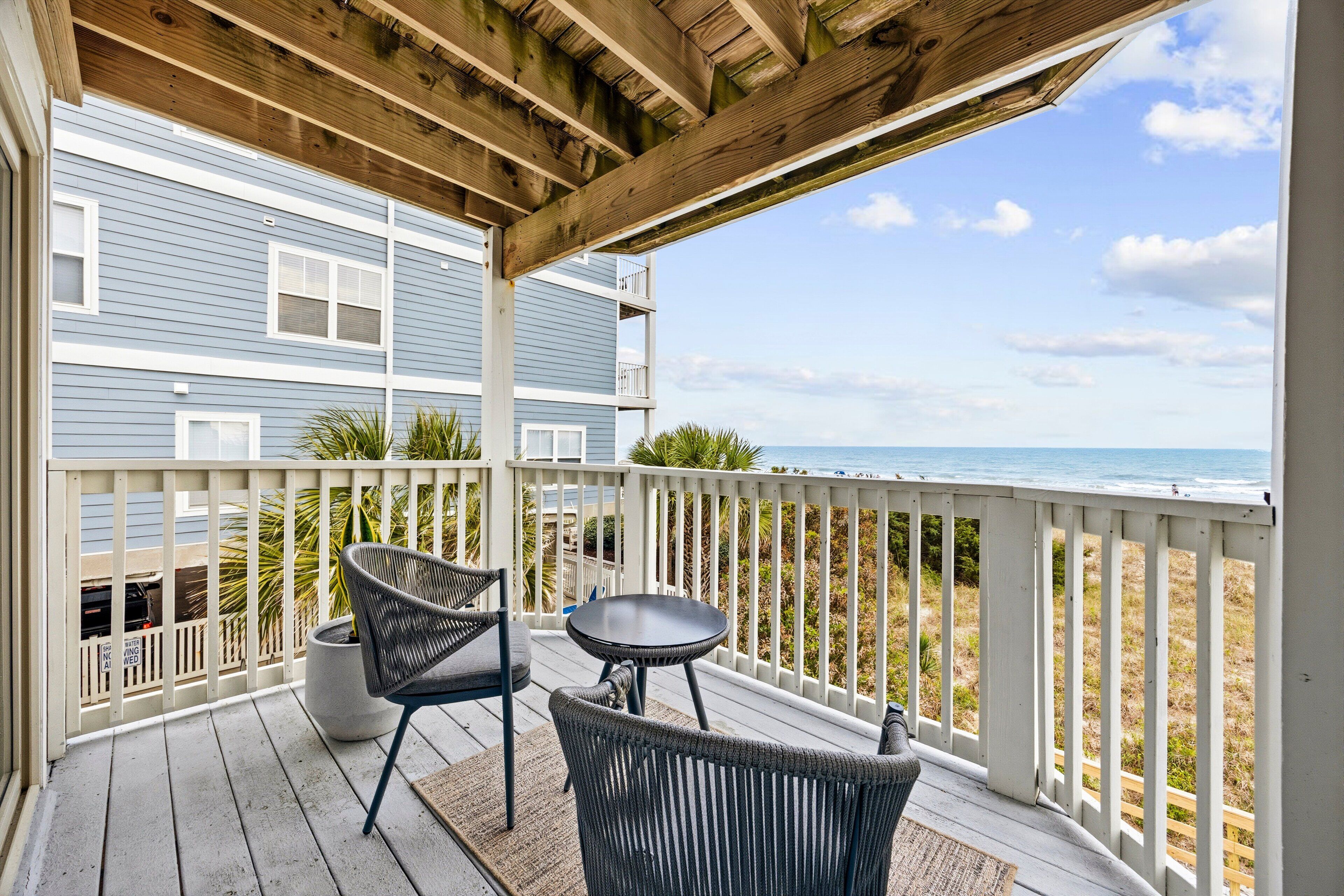 A wooden deck with a view of the beach and ocean.