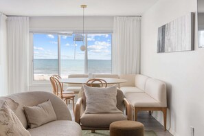 Ein Zimmer mit Meerblick, einem runden Esstisch und einer Couch.