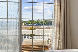 Ein Zimmer mit Blick durch ein Fenster, inklusive Balkon mit Stuhl und Tisch.