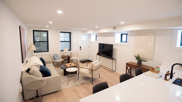 Un salon moderne avec un canapé, une table basse et un téléviseur. Il y a également un coin repas avec une table et des chaises.