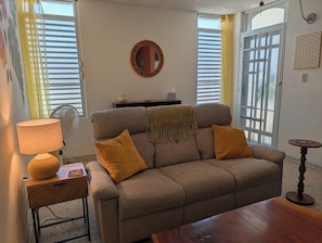 Ein Wohnzimmer mit einer Couch, einer Lampe, einem kleinen Tisch und einem Spiegel an der Wand.