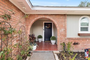 A brick house with a tiled entrance, a dark door, and potted plants.